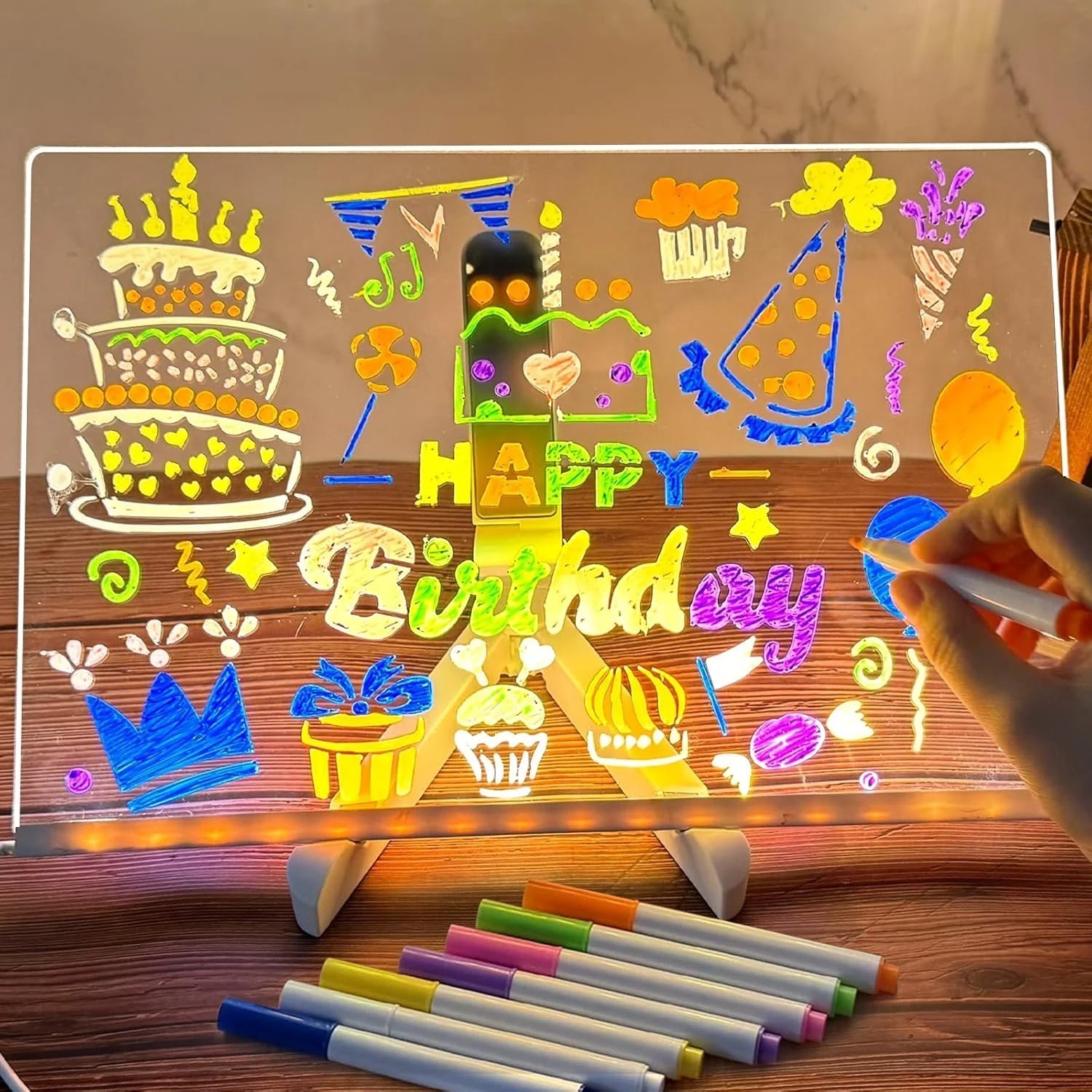 Light-up birthday-themed board with colorful markers on a wooden surface